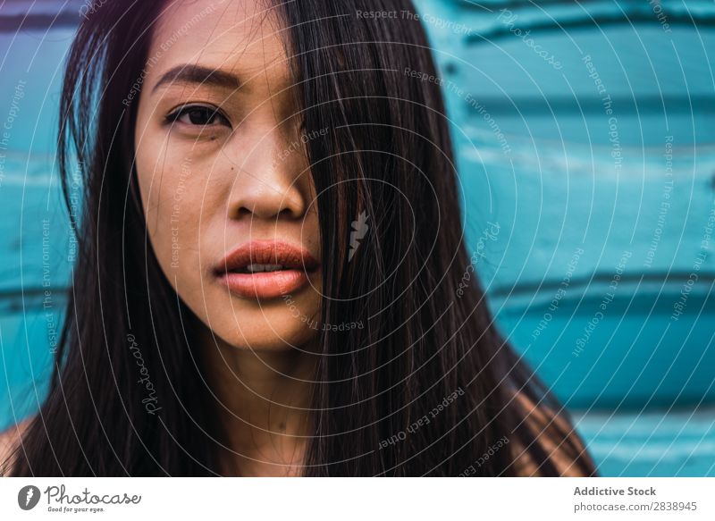 Nachdenkliche asiatische Frau, die sich an die blaue Tür lehnt. hübsch Jugendliche Fürsorge besinnlich Stoff anlehnen Straße Stadt schön Porträt attraktiv