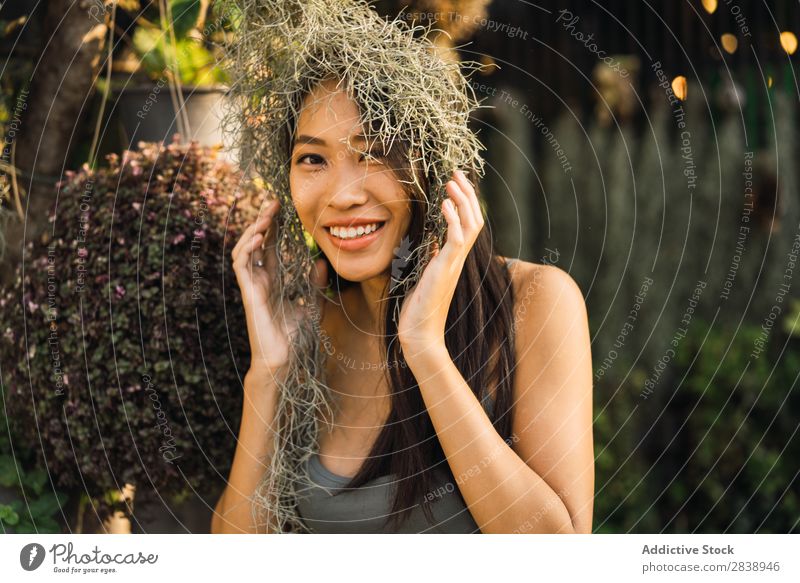 Fröhliche Frau mit trockenem Gras hübsch asiatisch Jugendliche regenarm Behaarung Körperhaltung heiter Lächeln schön Porträt attraktiv Beautyfotografie Mensch