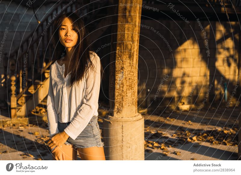Asiatin, die sich an die Säule lehnt. Frau hübsch asiatisch Jugendliche Behaarung brünett Freude Holz Haus Sonnenstrahlen schön Porträt attraktiv
