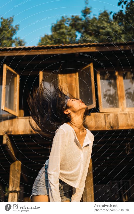 Hübsche Frau schüttelndes Haar zu Hause hübsch asiatisch Jugendliche Behaarung Schütteln brünett Freude Holz Sonnenstrahlen schön Porträt attraktiv