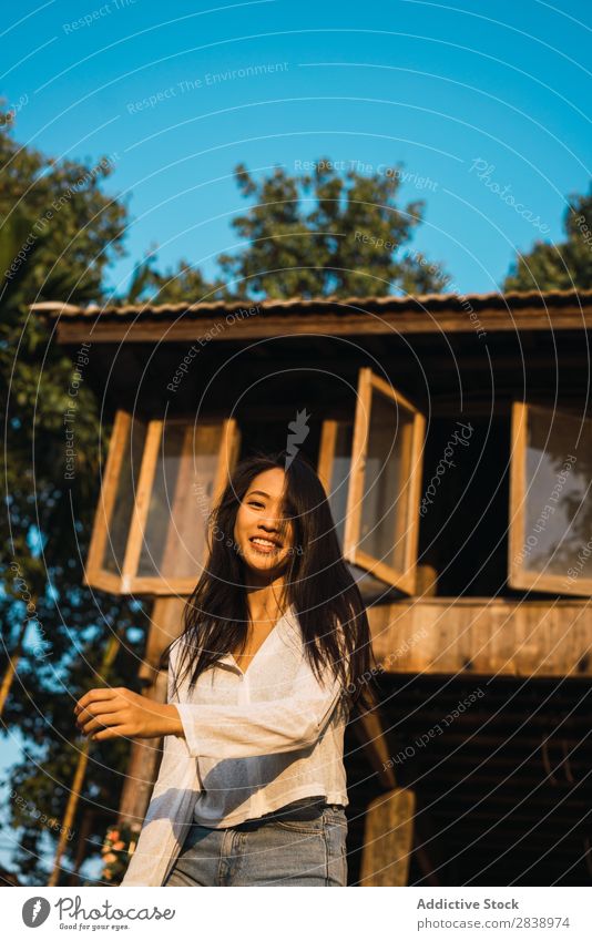 Hübsche Frau, die in der Nähe des Hauses posiert. hübsch asiatisch Jugendliche Behaarung Schütteln brünett Freude Holz Sonnenstrahlen schön Porträt attraktiv