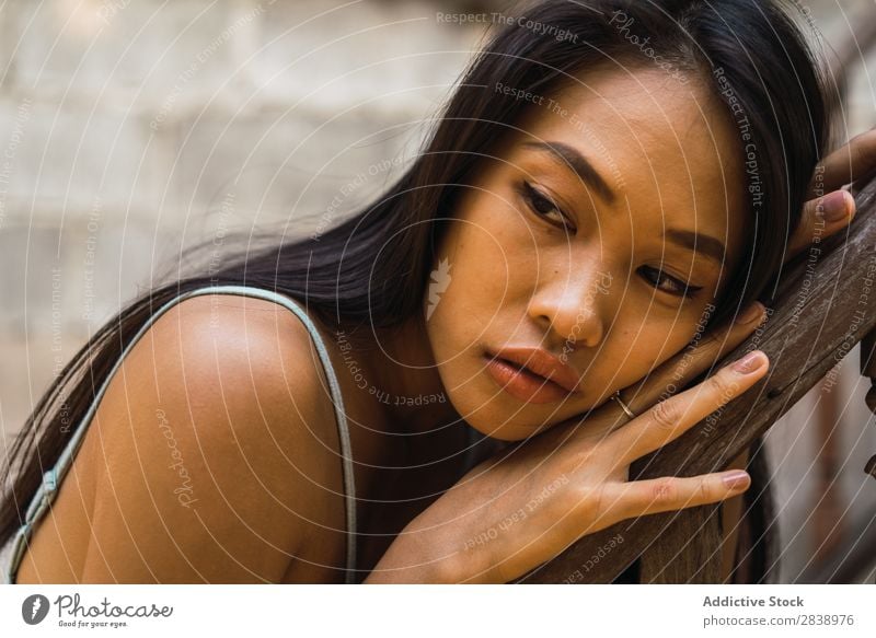Nachdenkliche Frau am Holzhandlauf hübsch asiatisch Jugendliche Fürsorge besinnlich anlehnen Geländer Wegsehen schön Porträt attraktiv Beautyfotografie Mensch