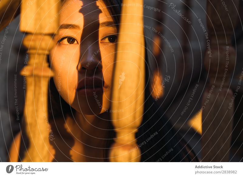 Nachdenkliche Frau auf der Treppe sitzend hübsch asiatisch Jugendliche Geländer Holz Freitreppe Abend Sonnenuntergang Fürsorge besinnlich schön Porträt