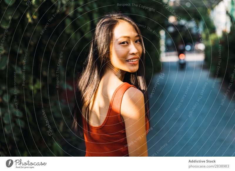Fröhliche Frau, die auf der Straße posiert. hübsch asiatisch Jugendliche heiter Glück Freude grün Stadt schön Porträt attraktiv Beautyfotografie Mensch niedlich