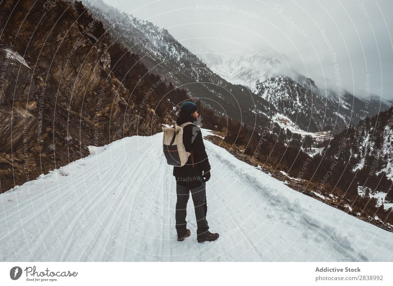 Mann, der auf einer verschneiten Straße posiert. Winter Hügel Berge u. Gebirge Schnee Landschaft Natur weiß Eis Jahreszeiten kalt Ferien & Urlaub & Reisen Weg