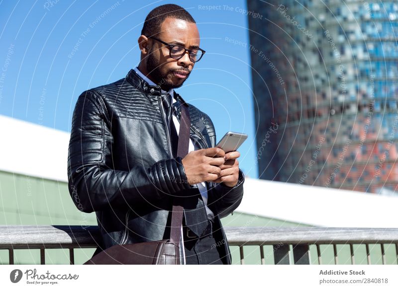 Junger Mann beim Tippen am Telefon gelungen Stil selbstbewußt Geschäftsmann Technik & Technologie benutzend Browsen Geschäftsleute Afrikanisch schwarz