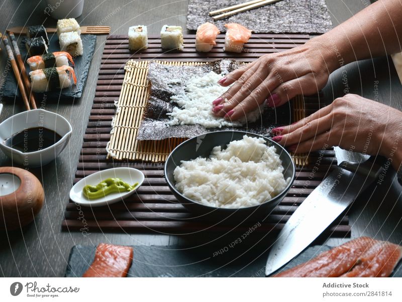 Frau bereitet zu Hause Sushi-Rollen zu. machen Hand Lebensmittel Reis vorbereitend Vorbereitung maki Essstäbchen Orientalisch Essen zubereiten Unterlage Seegras
