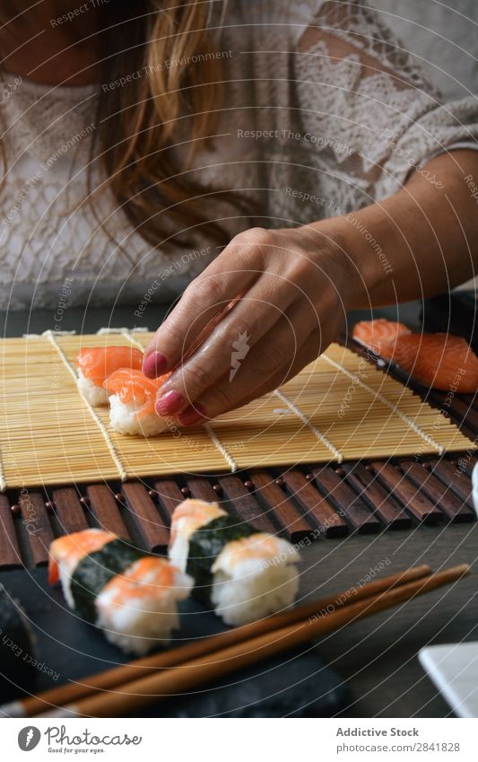 Frau bereitet zu Hause Sushi-Rollen zu. machen Hand Lebensmittel Reis vorbereitend Vorbereitung maki Essstäbchen Orientalisch Essen zubereiten Unterlage Seegras
