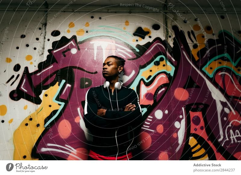 Selbstbewusster Mann posiert gegen Graffiti Körperhaltung einzigartig Stil Selbstständigkeit selbstbewußt schwarz Kopfhörer Großstadt Technik & Technologie