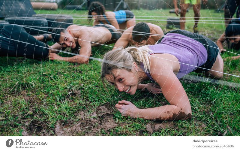 Teilnehmer des Hindernislaufs krabbeln unter Stromkabeln Freude Glück Sport Mensch Frau Erwachsene Mann Menschengruppe authentisch dreckig anstrengen Konkurrenz