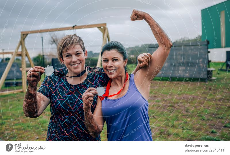 Zwei Sportlerinnen zeigen ihre Medaillen nach dem Rennen Glück Feste & Feiern Preisverleihung Erfolg Mensch Frau Erwachsene Arme Hand Lächeln authentisch stark