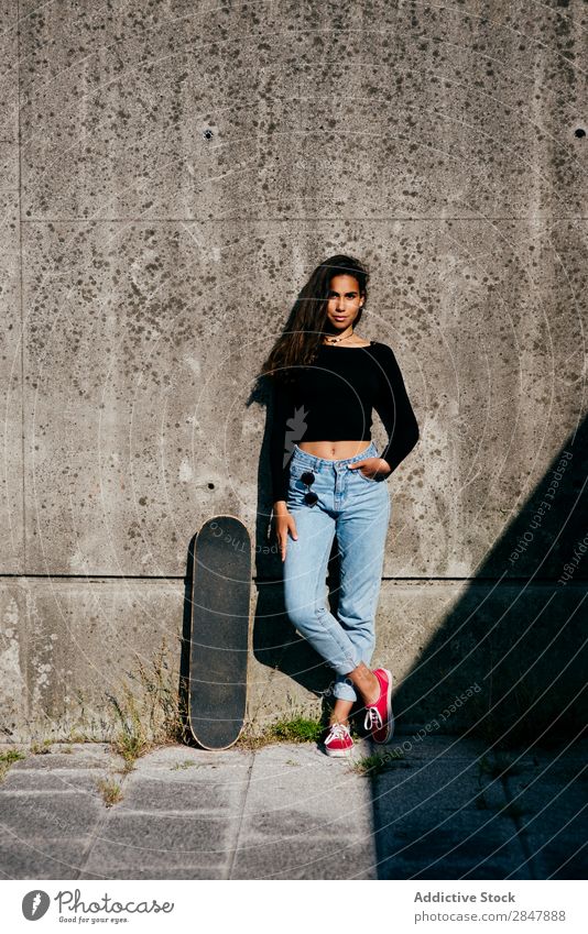 Stylisches Mädchen mit Skate Frau Stadt Skateboard Stil Bekleidung Kultur selbstbewußt Hände in den Taschen Skateboarding Jugendliche Sommer Schickimicki