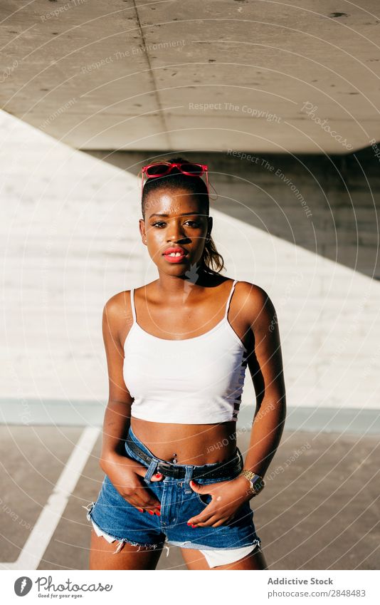Selbstbewusste schwarze Frau im Sonnenlicht Stil Sommer Körperhaltung Strukturen & Formen selbstbewußt aufreizend Stadt stehen Beautyfotografie Porträt trendy