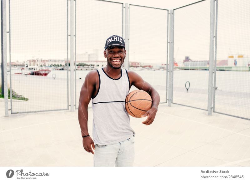Schwarzer Mann mit Basketball Ball ausdehnend Straßenball selbstbewußt Sportpark Stadt maskulin Sportler Stil Körperhaltung Afroamerikaner Freizeit & Hobby