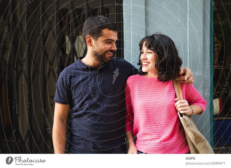 Glückliches junges Paar, das sich anlächelt. Lifestyle kaufen Freude schön Sommer Frau Erwachsene Mann Freundschaft Straße T-Shirt Pullover brünett Vollbart