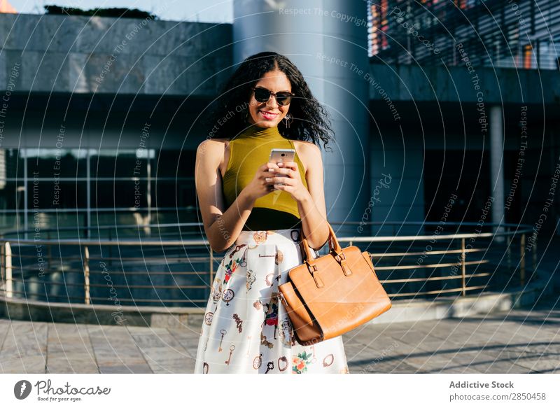 Lächelnde Frau mit Smartphone in der Stadt PDA Großstadt elegant Texten benutzend Browsen laufen Mitteilung Jugendliche Lifestyle schön Mädchen Mobile lässig