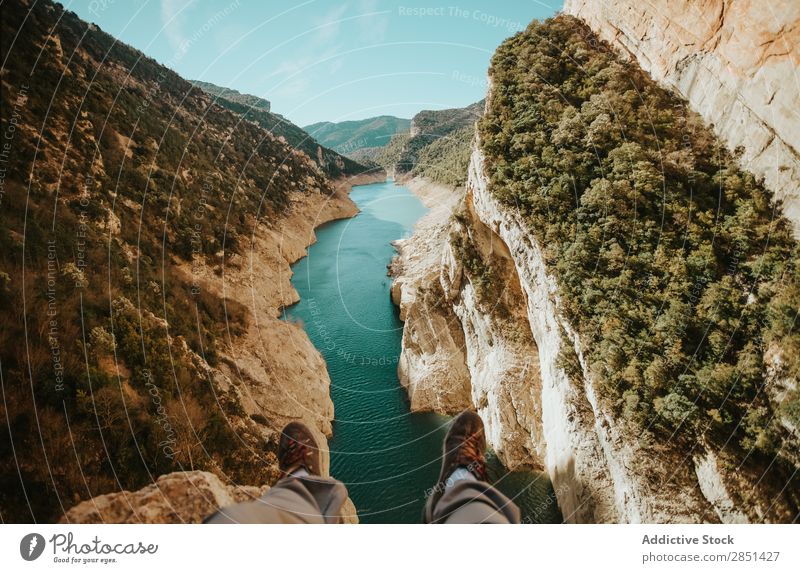 Beine eines Mannes, der am Rande des Mont-Rebei Canyons, Lleida, Spanien, sitzt. Schlucht Fluss Landschaft Mensch Feldfrüchte unkenntlich Körperteil Natur