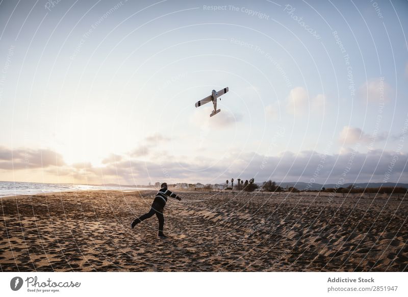 Ein Mann an einem Strand, der das Spielzeugflugzeug wirft. Mensch Flugzeug Spielen werfen Etage Glück Freude Lifestyle träumen kindisch Abend Küste Meer Wasser