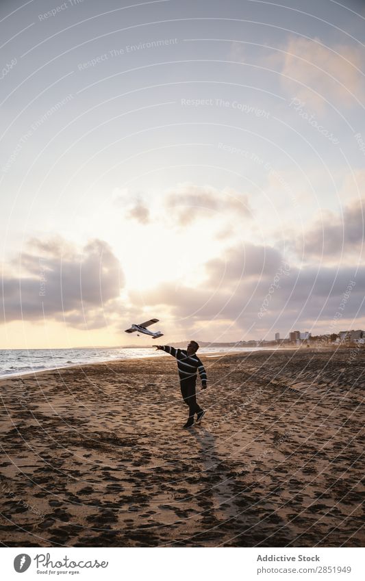 Ein Mann an einem Strand, der das Spielzeugflugzeug wirft. Mensch Flugzeug Spielen werfen Etage Glück Freude Lifestyle träumen kindisch Abend Küste Meer Wasser