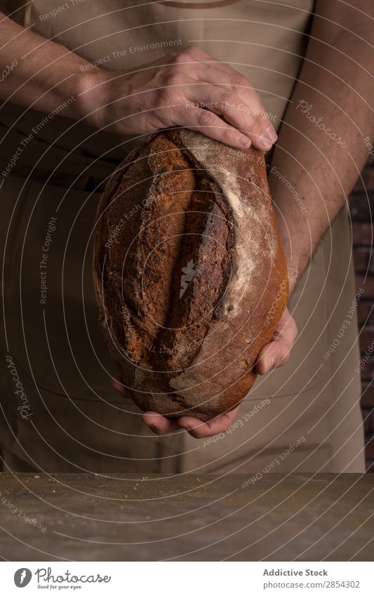 Ein Mann hält einen frisch gebackenen Brotlaib. Bäckerei Frühstück Kohlenhydrat geschnitten dunkel Mehl Lebensmittel Hand selbstgemacht selbstgebacken gebastelt
