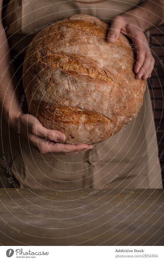 Ein Mann hält einen frisch gebackenen Brotlaib. Bäckerei Frühstück Kohlenhydrat geschnitten dunkel Mehl Lebensmittel Hand selbstgemacht selbstgebacken gebastelt
