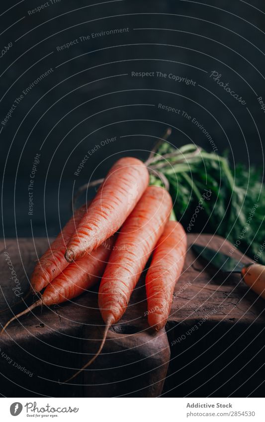 Frische Karotten in einem Holzschneidebrett Hintergrundbild Bündel Möhre mehrfarbig dunkel Lebensmittel frisch Ernte Gesundheit Messer Metall Ernährung Orange