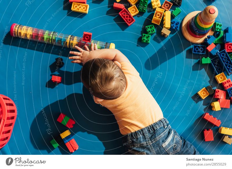 Frohes Baby beim Spielen mit Spielzeugblöcken. Kinderbetreuung Kindergarten Schule Kleinkind Junge klein LEGO Glück Fürsorge Etage niedlich Freude Vorschule