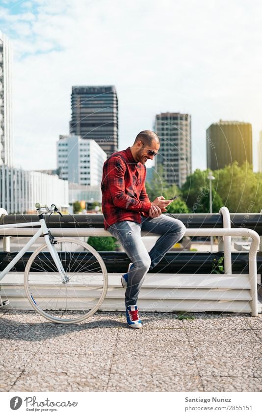 Junger Mann mit Handy und festem Fahrrad. Mobile Fixie Telefon Schickimicki Lifestyle stehen Fahrradfahren Großstadt Gebäude Solarzelle Stadt Mensch