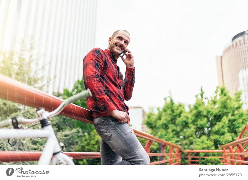 Junger Mann mit Handy und festem Fahrrad. Mobile Fixie Telefon Schickimicki Lifestyle stehen Fahrradfahren Großstadt Gebäude Solarzelle Stadt Mensch