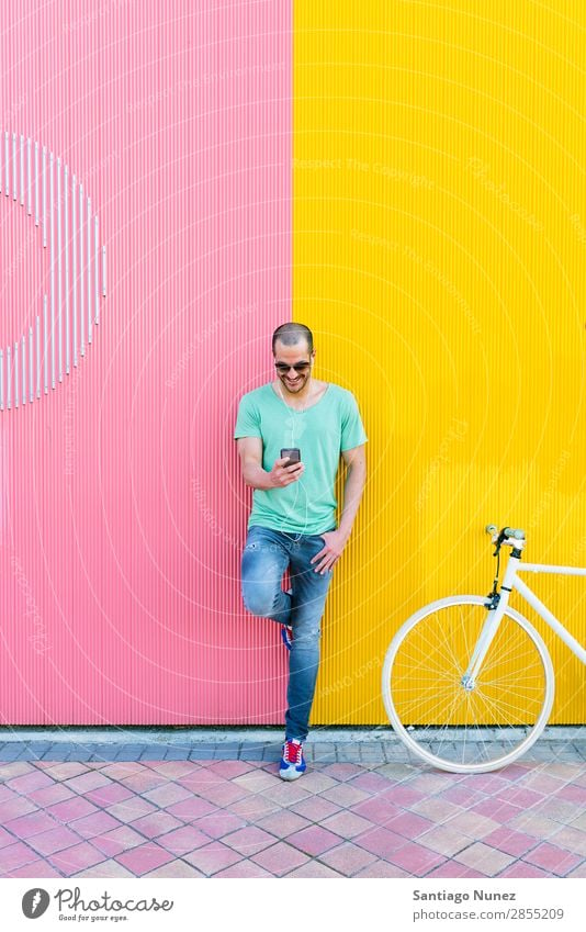 Gutaussehender junger Mann mit Handy und festem Fahrrad. Mobile Fixie Telefon Schickimicki Lifestyle stehen Fahrradfahren Großstadt Solarzelle Stadt Mensch