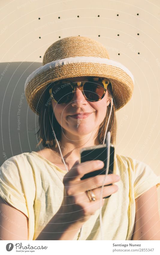 Schöne junge Hipsterin kaukasische Frau mit Smartphone und Kopfhörern, SMS und Musik hören. schön lässig Kaukasier Solarzelle Handy Chatten Mädchen Glück Hut
