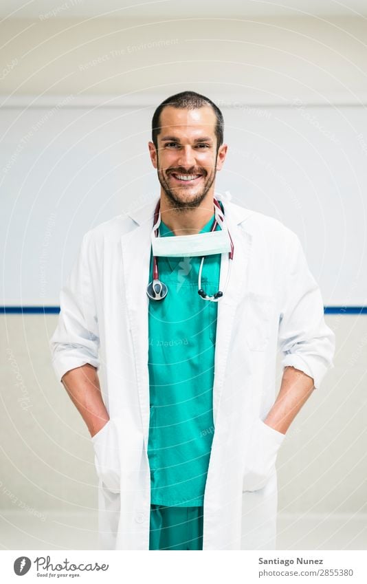 Lächelnder, gutaussehender Arzt im Krankenhaus. Stehend. Arme Hintergrundbild Fürsorge Kaukasier heiter Klinikerin Gerät Freundlichkeit Glück Gesundheit