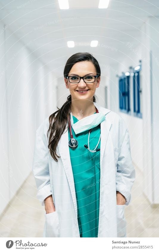 Lächelnd schöner Arzt im Krankenhaus. Stehend. Arme attraktiv Hintergrundbild Fürsorge Kaukasier heiter Klinik Klinikerin Gerät Frau Freundlichkeit