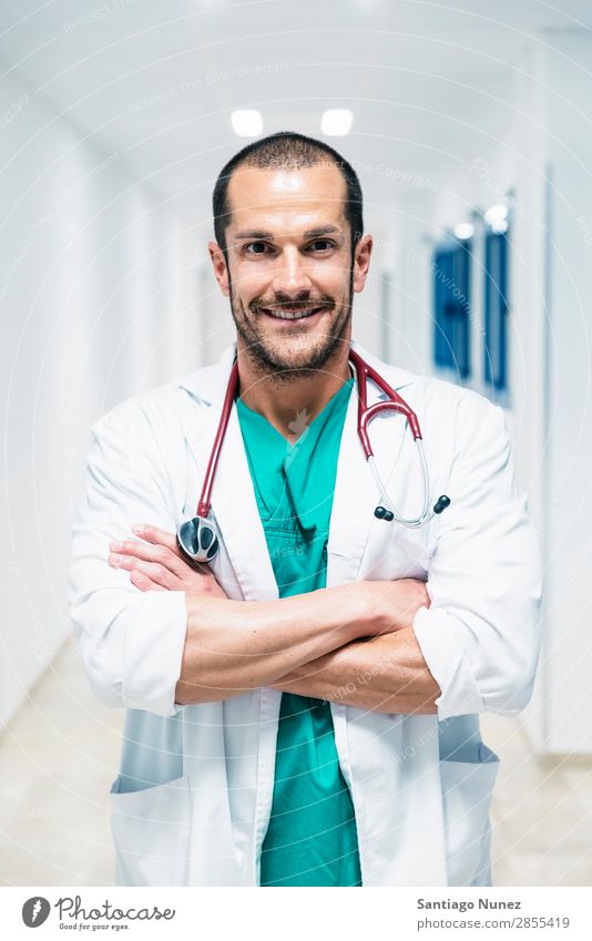 Lächelnder, gutaussehender Arzt im Krankenhaus. Stehend. Arme Hintergrundbild schön Fürsorge Kaukasier heiter Klinik Klinikerin Gerät Freundlichkeit