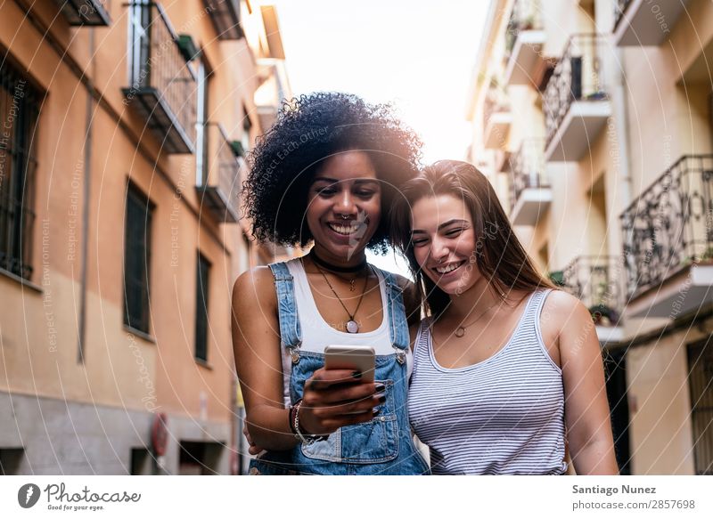 Schöne Frauen, die ein Handy auf der Straße benutzen. Freundschaft Jugendliche Großstadt Glück Sommer Mensch Freude Mobile PDA Telefon Solarzelle benutzend