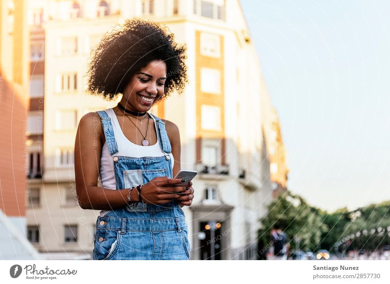 Schöne Frau mit Handy auf der Straße. Telefon schwarz Afrikanisch Mobile PDA Texten Mitteilung Afro-Look Mensch Porträt Großstadt Jugendliche Mädchen Amerikaner