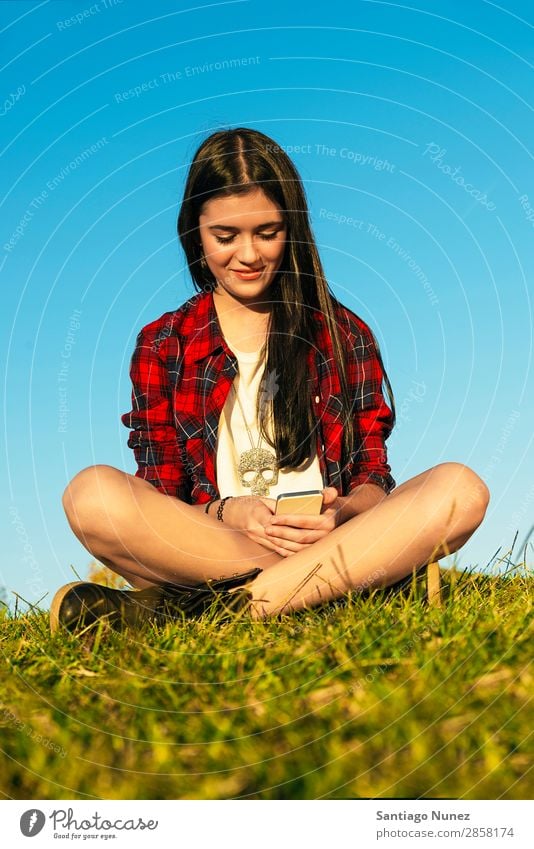 Fröhliches Teenager-Mädchen mit Handy im Park Jugendliche Mobile Mitteilung Amerikaner attraktiv schön Halterung Kaukasier Solarzelle Kommunikation Frau