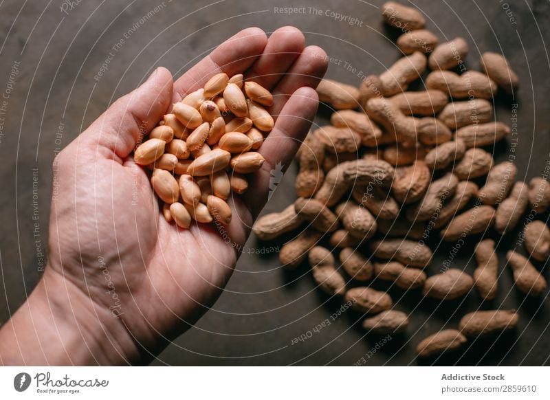 Mann hält Erdnüsse in der Hand. Landwirtschaft Sortiment Hintergrundbild Schneidebrett regenarm Lebensmittel frisch Frucht Gesundheit Halt Zutaten Nuss roh