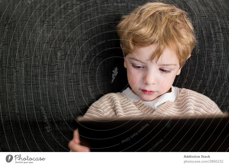 Blonder und süßer Junge spielt mit dem Tablett. blond Kaukasier Kind Computer Tag digital elektronisch im Innenbereich Lifestyle Spielen Bildschirm