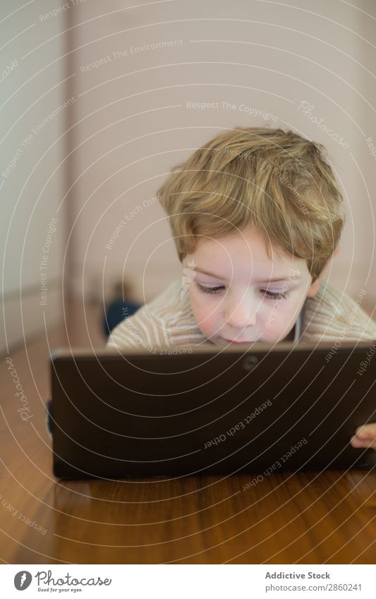 Blonder und süßer Junge spielt mit dem Tablett. blond Kaukasier Kind Computer Tag digital elektronisch im Innenbereich Lifestyle Spielen Bildschirm