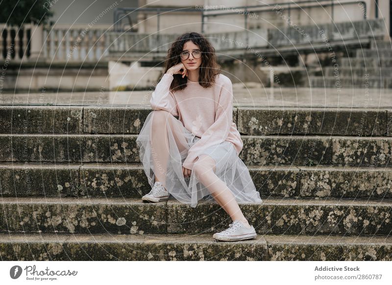 Stylische Frau im Rock auf der Treppe sitzend Stil Freitreppe Brillenträger Turnschuh hübsch Kleid trendy romantisch Imkerschleier brünett nass