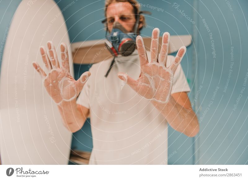 Mann in Atemschutzmaske mit Händen im Staub Atemschutzgerät Hand Werkstatt Surfbrett zeigen Holz Handfläche Schreinerei Arbeitsplatz Verschnaufpause Zimmerer