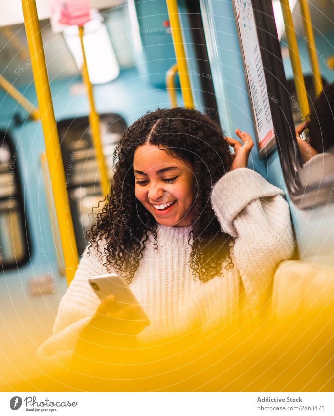 Lächelnde schwarze Frau mit Smartphone im Transport PDA Verkehr Afroamerikaner lockig Behaarung benutzend attraktiv Glück Browsen Handy urwüchsig Jugendliche