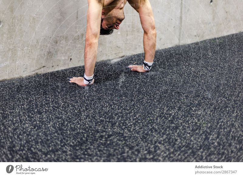 Mann macht Handstand im Fitnessstudio Sporthalle Presse ohne Hemd Wand Training Gerät Jugendliche grau Athlet Körper sportlich Gleichgewicht Gesundheit üben
