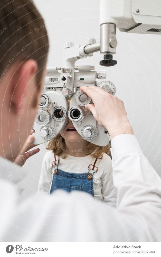 Optiker testet die Augen eines Mädchens. Klinik Gerät diagnostizieren Anzeige Arzt Prüfung & Examen Brillenträger Gesundheit Krankenhaus Hygiene Kind Medikament