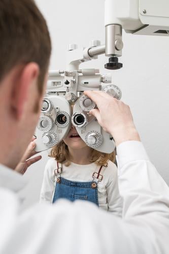 Optiker testet die Augen eines Mädchens. Klinik Gerät diagnostizieren Anzeige Arzt Prüfung & Examen Brillenträger Gesundheit Krankenhaus Hygiene Kind Medikament