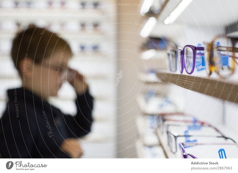 Kleiner Junge beim Anprobieren einer Brille Kind Auge Mode Brillenträger Linse Ophtalmologe Optiker Augenoptikerin Optometrie Blick Sonnenbrille Sehvermögen