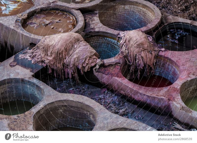 Haufen von verschmutzten Textilien in der Nähe von Containern mit Farbstoffflüssigkeit dreckig liquide Farbmittel Marrakesch Marokko Stein Anhäufung Staubwedel
