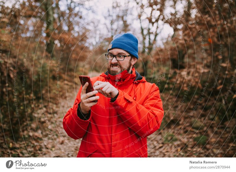 Junger Mann kämpft mitten im Wald mit seinem Handy und versucht, es zum Laufen zu bringen Lifestyle schön Ferien & Urlaub & Reisen Tourismus Ausflug Abenteuer