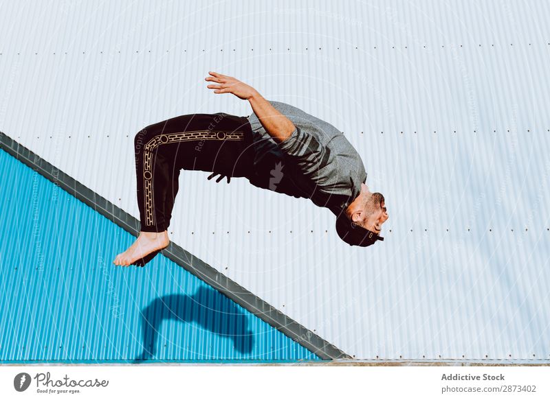 Trendiger Mann, der auf der Straße umdreht. Flip Barfuß springen Wand Gebäude Breakdancer Stunt Stil lässig trendy Fitness Lifestyle Freizeit & Hobby üben